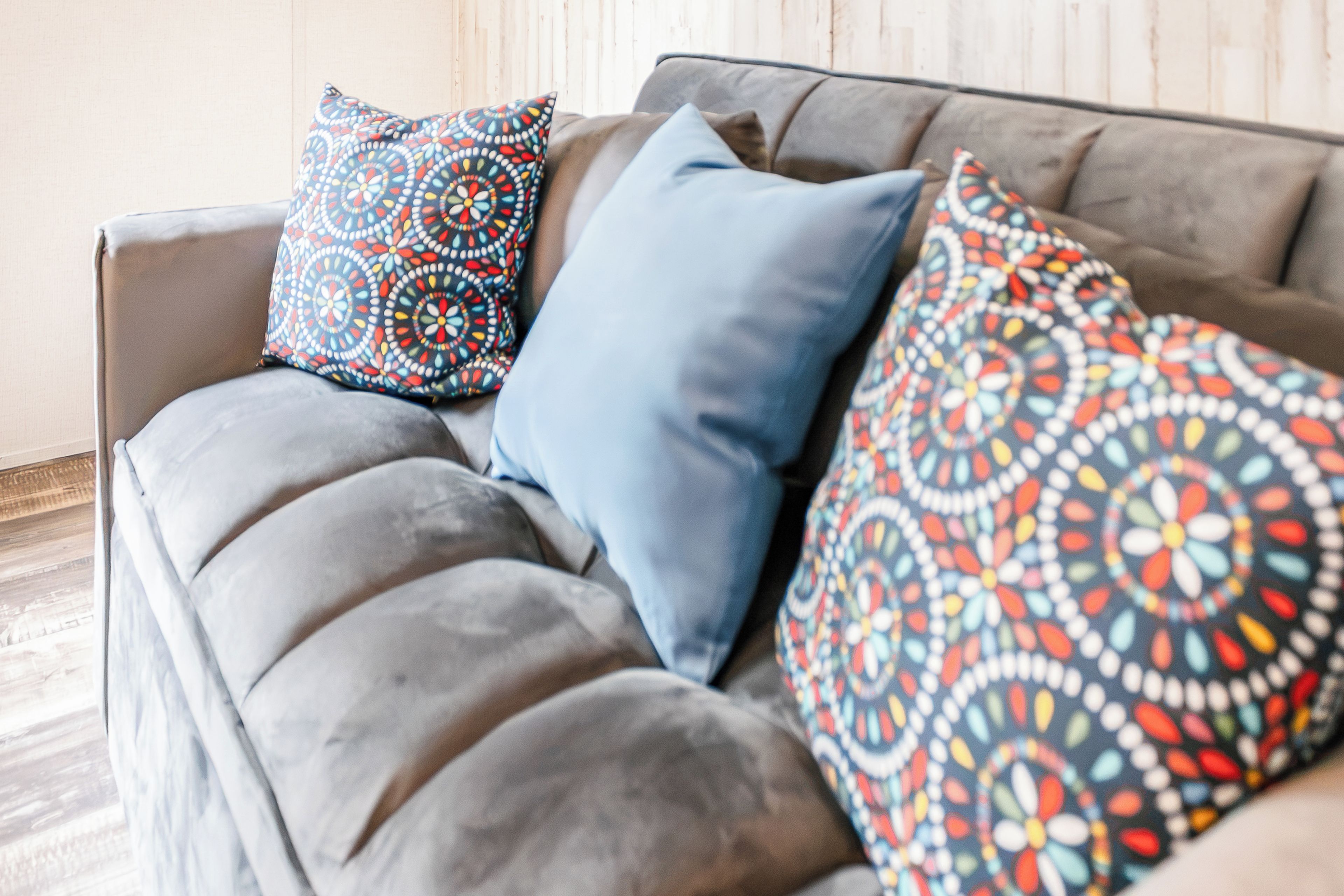 Un canapé gris avec trois coussins à motifs.