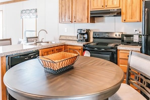 A kitchen with wooden cabinets, a stainless steel dishwasher, a coffee maker, and a stove. - Bronson - Wildlife Escape (Bronson)