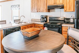 Una cocina con gabinetes de madera, lavavajillas de acero inoxidable, cafetera y estufa.