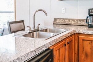 Una cocina con un lavamanos de acero inoxidable doble, un mueble de madera y una encimera.