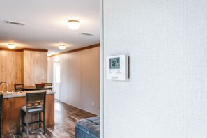 A modern kitchen with wooden cabinets and a dining area with a blue upholstered chair. - Bronson - Wildlife Escape (Bronson)