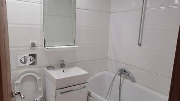 Een badkamer met toilet, wastafel, spiegel en bad.