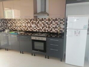A kitchen with a gas stove, oven, and a white refrigerator.