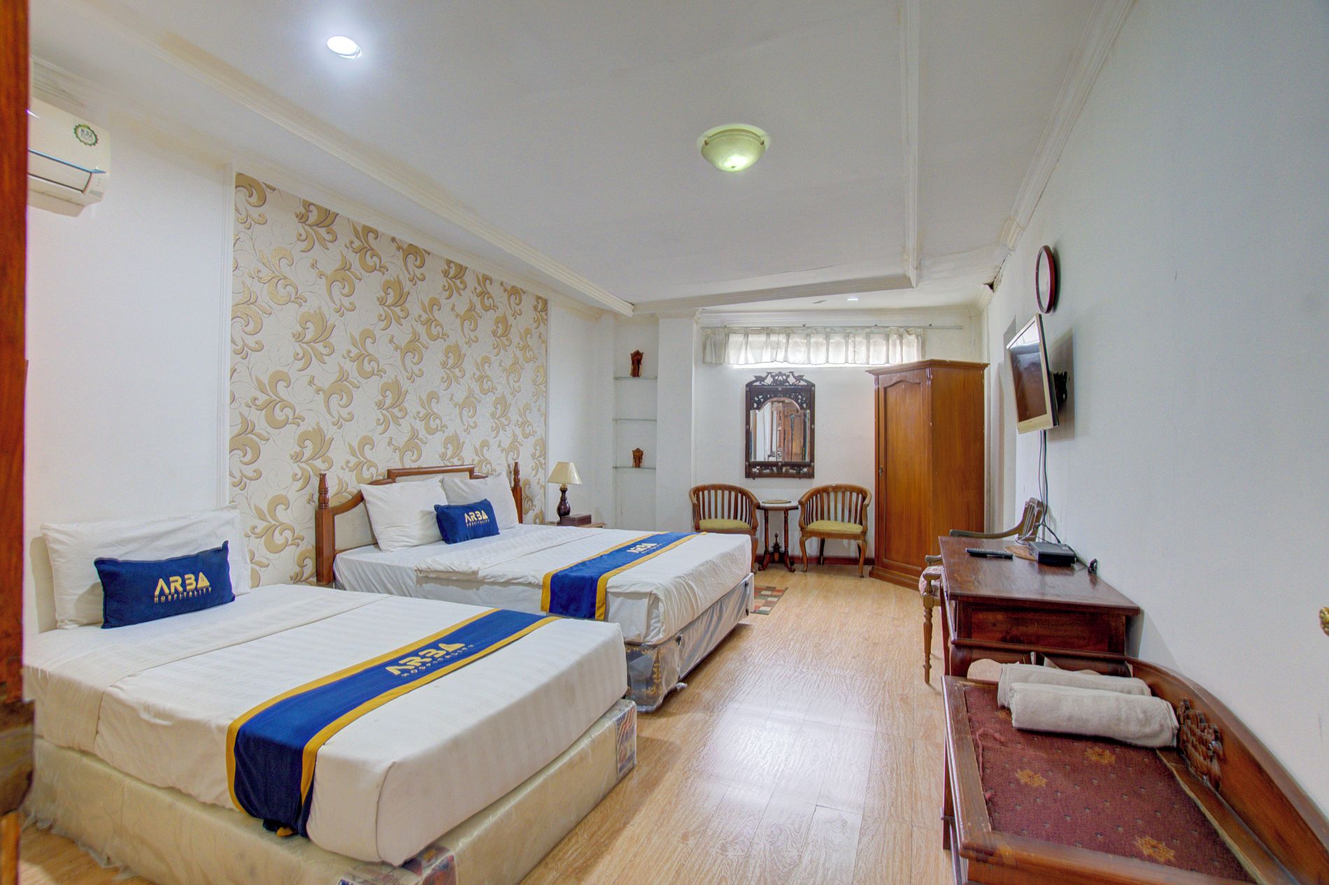 A hotel room with two beds, a desk, a chair, a television, and a mirror.