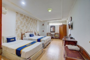 A hotel room with two beds, a desk, a chair, a television, and a mirror. - ETHNIC Hotel By CQA (Bandung)