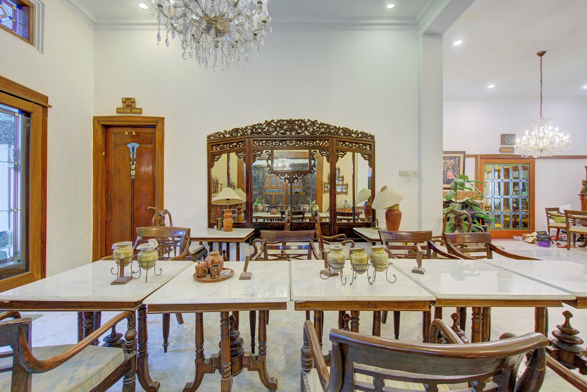 Un comedor con un espejo grande y ornamentado, sillas de madera y una araña.