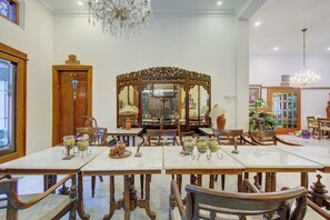 Un comedor con un espejo grande y ornamentado, sillas de madera y una araña.