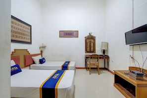 A hotel room with two beds, a desk, a television, and a wall-mounted decorative piece. - ETHNIC Hotel By CQA (Bandung)