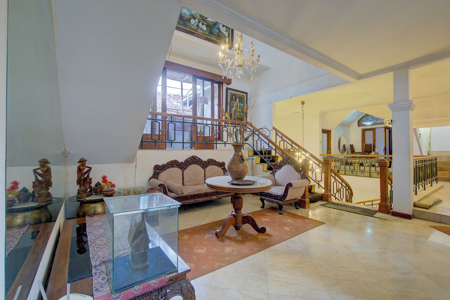 A spacious living area with a high ceiling, a staircase, and a chandelier.