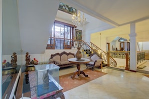 A spacious living area with a high ceiling, a staircase, and a chandelier. - ETHNIC Hotel By CQA (Bandung)