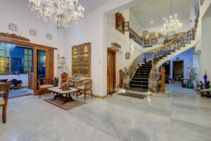 Un vestíbulo amplio con una imponente escalera, pisos de mármol y detalles decorativos elaborados.