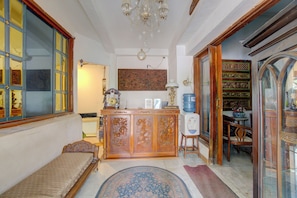 A room with a bed, a wooden cabinet, a water dispenser, and a chandelier. - ETHNIC Hotel By CQA (Bandung)