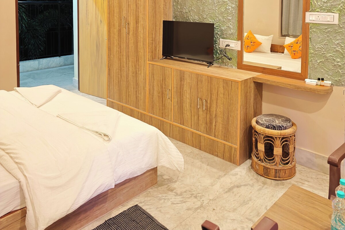 A hotel room with a bed, a television on a wooden cabinet, a bathroom with a mirror, and a ceiling fan.