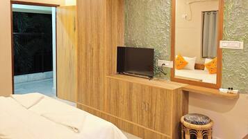 A hotel room with a bed, a television on a wooden cabinet, a bathroom with a mirror, and a ceiling fan.