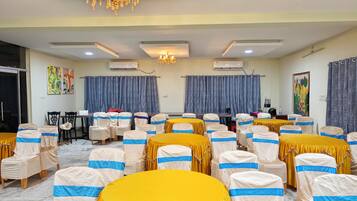 A conference room with round tables, chairs, and a chandelier.