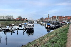 A canal with boats docked, a bridge, and buildings in the background. - Holiday apartment with 3 bedrooms (Zoutelande)