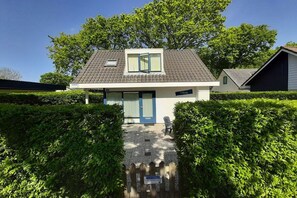 A modern two-story house with a sloped roof, a front door, and a small window. - Holiday apartment with 3 bedrooms (Zoutelande)