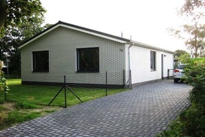 Un bâtiment d’un seul étage, avec une façade en briques, une allée pavée et une cour clôturée.