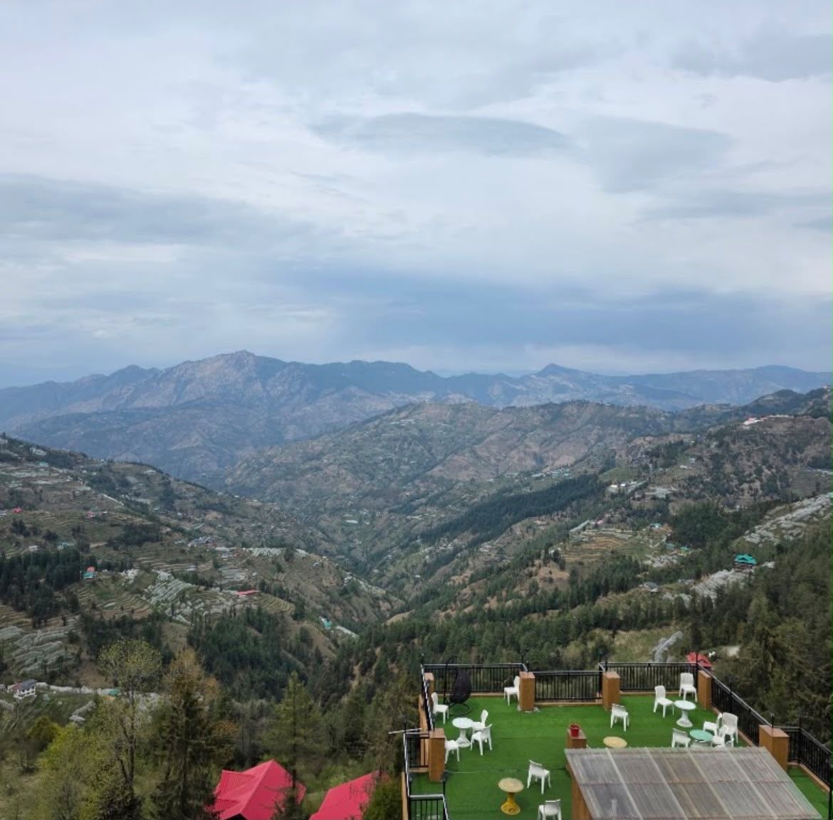 A terrace with outdoor seating overlooking a mountainous landscape.