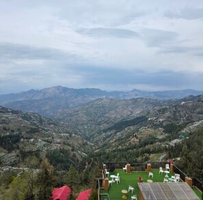 Una terraza con mobiliario exterior con vistas a un paisaje montañoso.