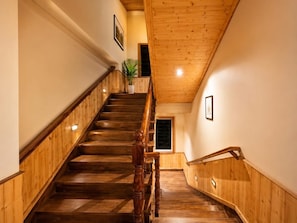 Una escalera de madera con barandilla, que conduce a un piso superior.