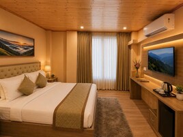 Habitación de hotel con cama, mesita de noche, televisor y un ventanal grande con cortinas.