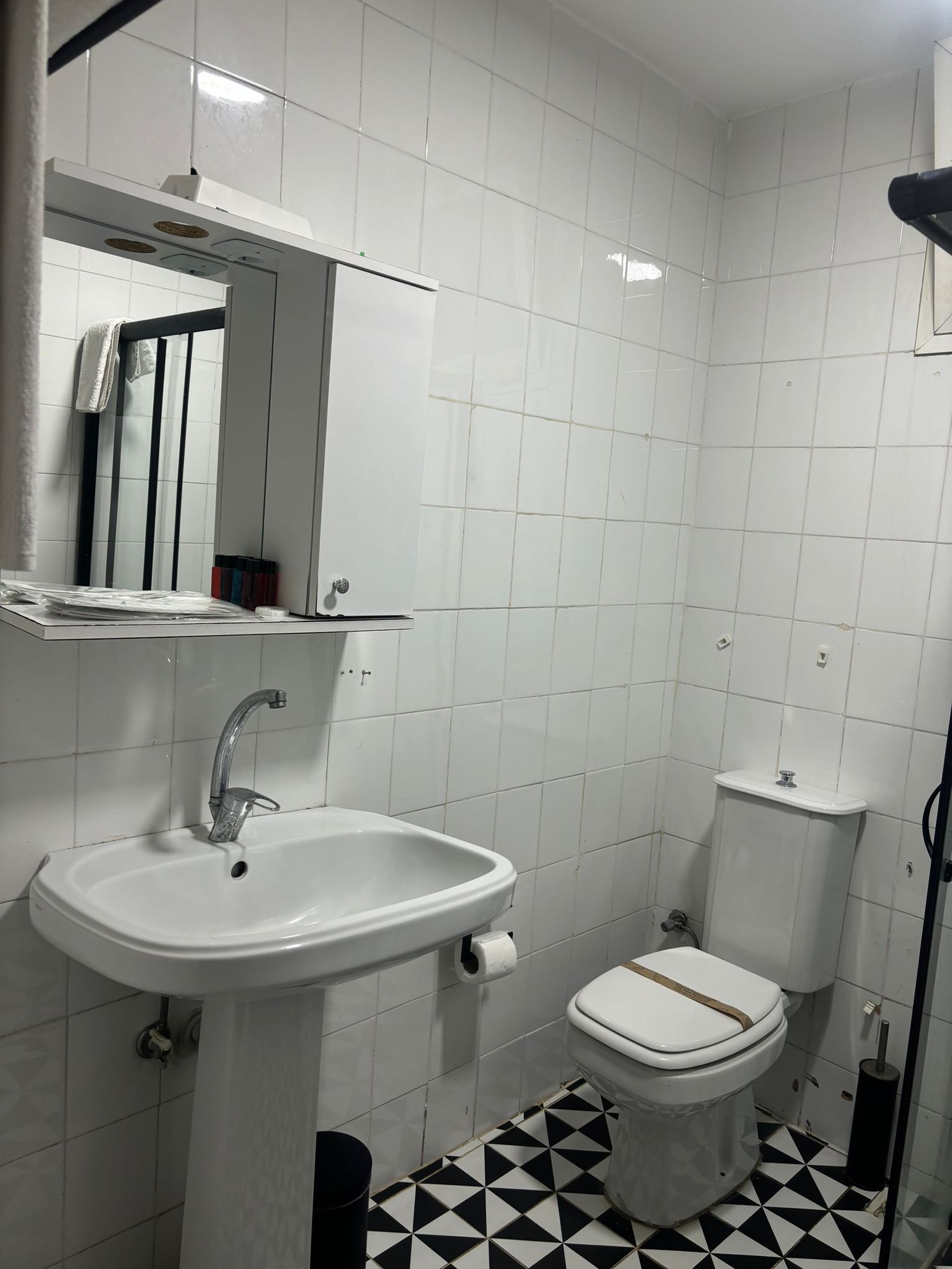 Casa de banho com lavatório branco, sanita e espelho sobre o lavatório.