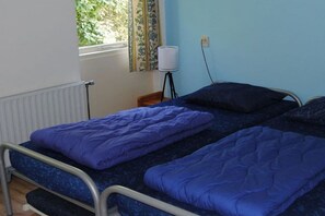 A single-bed room with a metal frame, a window with a view of greenery, and a bedside lamp. - De Branding 53, Kustlicht, ZOUTELANDE (ZOUTELANDE)
