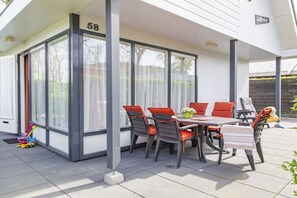 A covered patio area with a table and chairs, a number '58' sign, and a toy truck on the ground. - De Golbreker Type 1AC (Zoutelande)