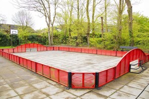 A basketball court with a red safety barrier and a bench. - The Golf Breaker - Type 1 (Zoutelande)