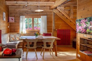 A wooden cabin interior with a dining area, a red radiator, and a television on the right. - Pifrailerhof "Alte Mühle" (Schnals - Südtirol)