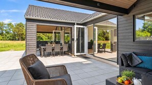 Ein überdachter Patio-Bereich mit Esstisch und einer Couch.