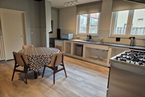 A compact kitchen with a dining area, a stove, and a window providing natural light. - Holiday home in Cadzand with swimming pool (Cadzand)