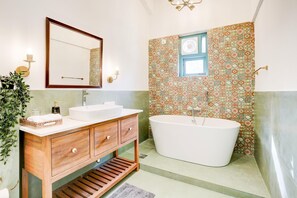 Ein Badezimmer mit einem Holzbadschränken, einer freistehenden Badewanne und Fliesen mit Muster.