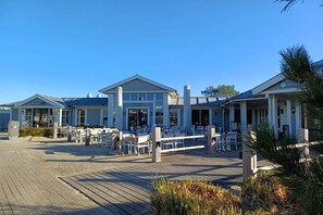 A waterfront hotel with outdoor seating and a boardwalk. - Holiday home "Zee Gras" (Kamperland)