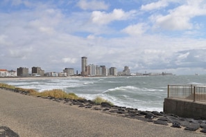 Eine Küstenstadt mit Uferpromenade, Meer und einem in der Ferne liegenden Steg.