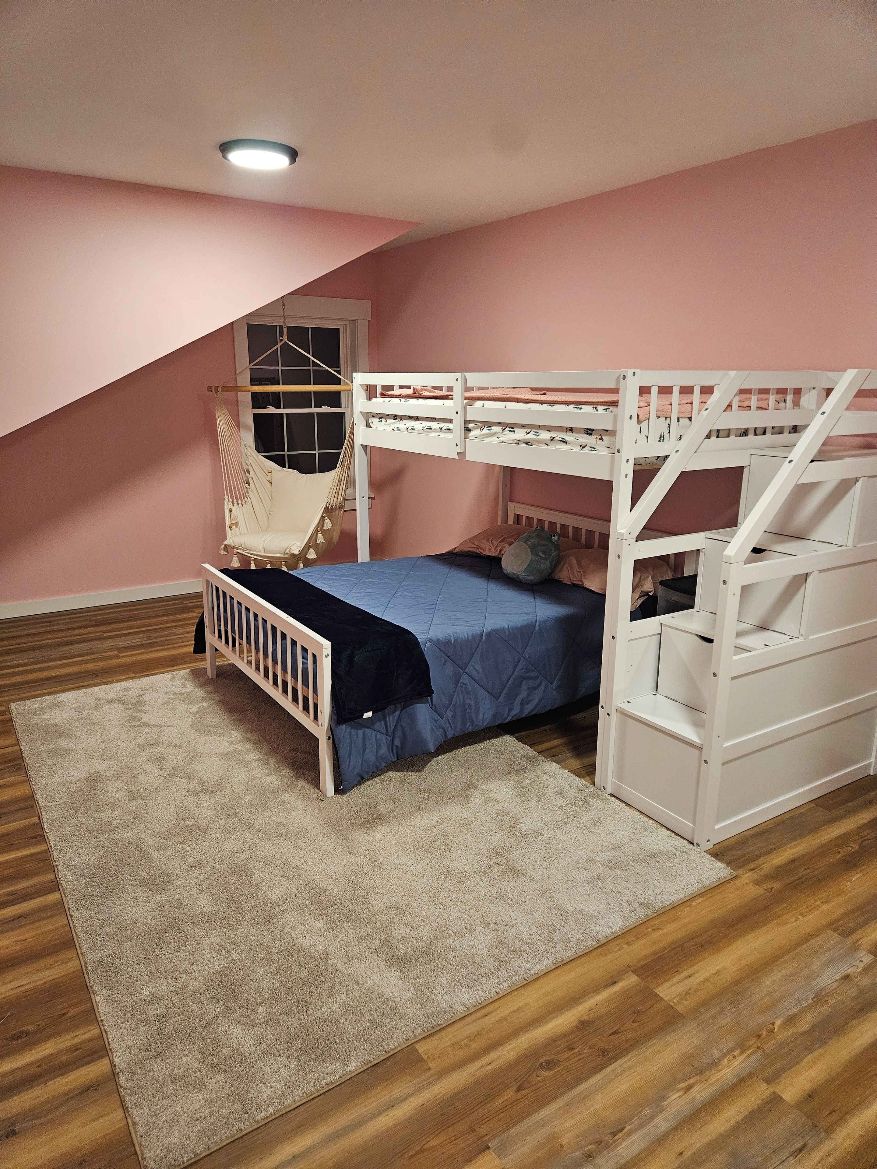 A bunk bed with a hammock, a window, and a wooden floor.