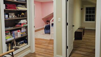 A hallway with a wooden floor, a bookshelf filled with board games, and a sign indicating 'MOONSHADOW' and 'TUCKERED OUT' areas.