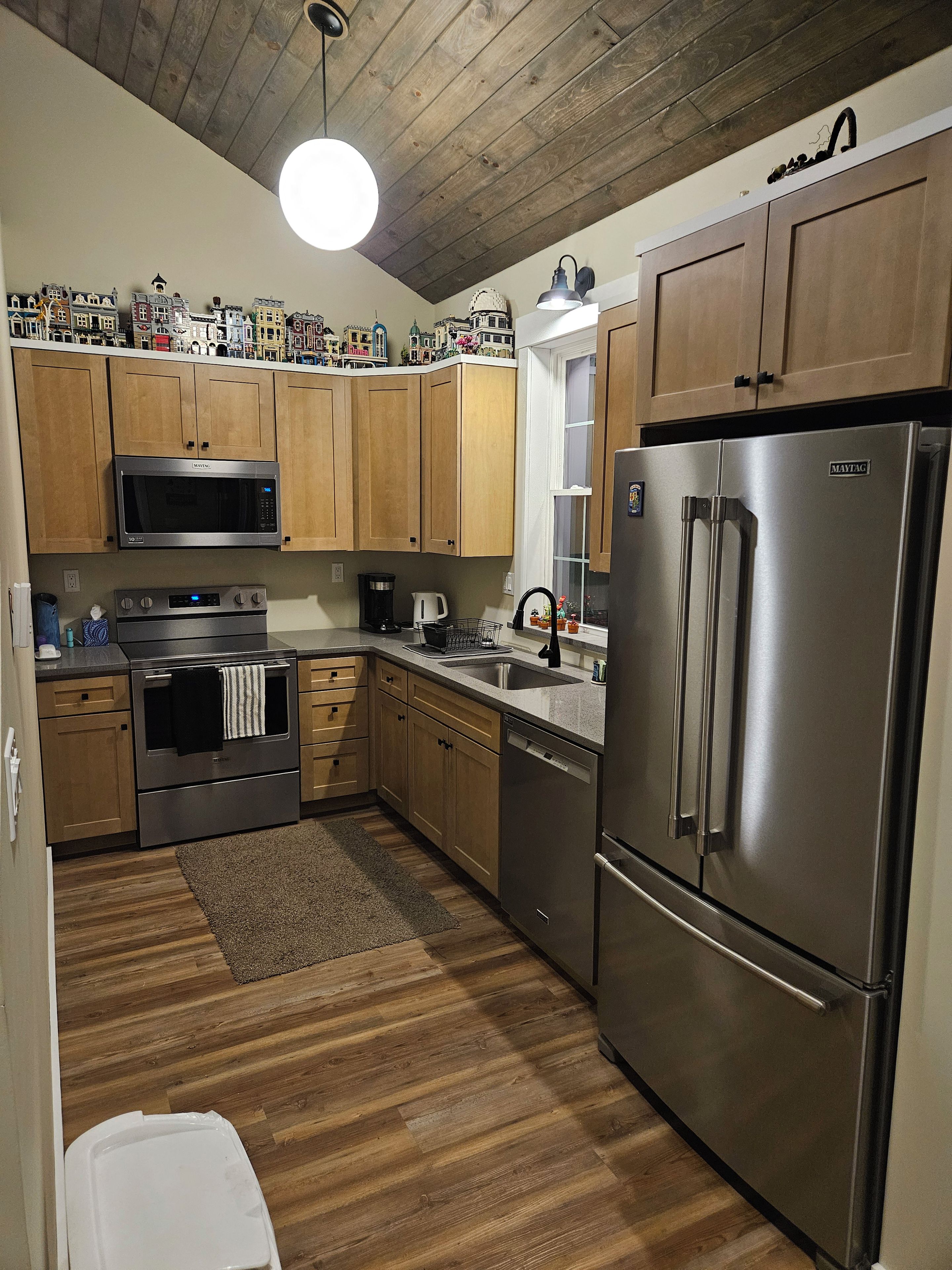 A kitchen with wooden cabinets, a stainless steel refrigerator, a microwave, an oven, and a coffee maker.