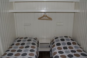 A small, single-room accommodation with two beds, each with a polka dot bedspread. There is a white bedside table between the beds, and a wooden hanger is visible on the wall above. - Holiday apartment in Zoutelande with Wi-Fi (Zoutelande)
