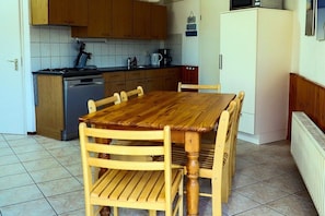 Une cuisine avec des meubles de rangement en bois, une cuisinière, un évier et une table à manger avec des chaises.