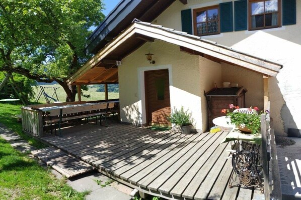 Une terrasse en bois avec un banc, une table et un pot de fleurs.