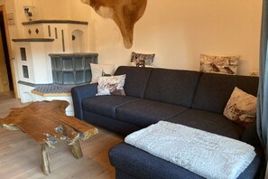 Ein Wohnzimmer mit einem dunkelblauen Sofa, einem Holztisch und einer weißen Decke.