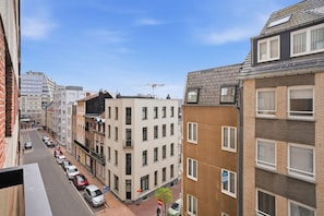 Un immeuble à plusieurs étages, avec un parking devant, un ciel dégagé et une grue de construction visible au loin.