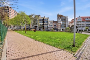 Un chemin pavé bordé d’une pelouse, entouré d’immeubles résidentiels à plusieurs étages.