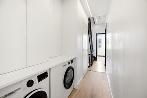 Une buanderie équipée d’un lave-linge Bosch, d’un sèche-linge et d’un plan de travail blanc.