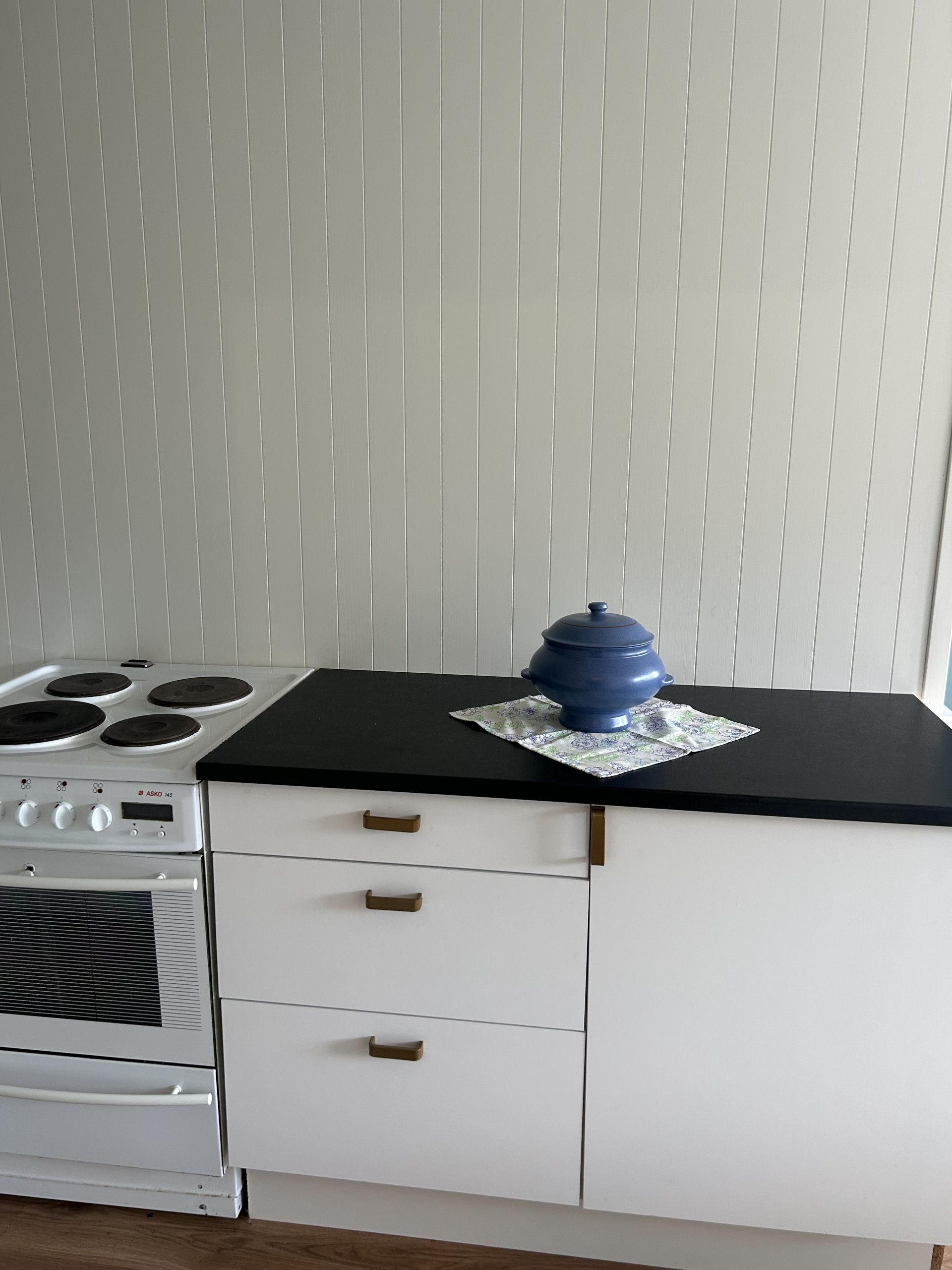 Une cuisine équipée d’une cuisinière, d ’un four et d’une casserole bleue posée sur le plan de travail.
