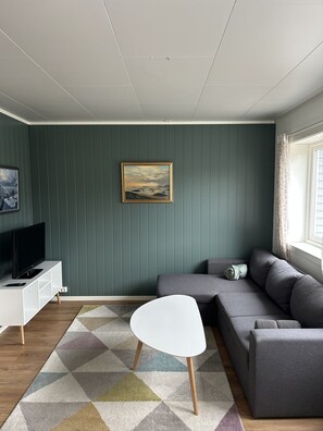 A modern living room with a grey sofa, a white coffee table, a flat-screen TV, and a painting on the wall. - Solhaug apartment, Fredvang (Flakstad)