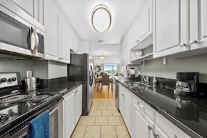 A modern kitchen with stainless steel appliances, a black countertop, and a view to the dining area. - Fantastic 2-bedroom apartment with AC in Marina del Rey (Marina del Rey)