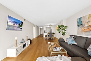 Ein modernes Wohnzimmer mit einer Couch, einem Couchtisch und einem Essbereich im Hintergrund.